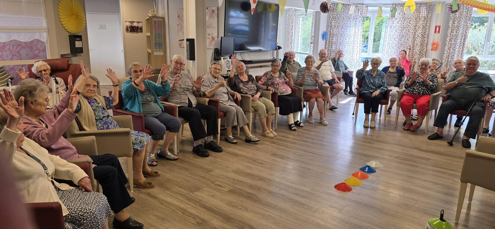 Atelier CREADIAZ® : un groupe de seniors assis sur des chaises, les mains levées en mouvement guidé