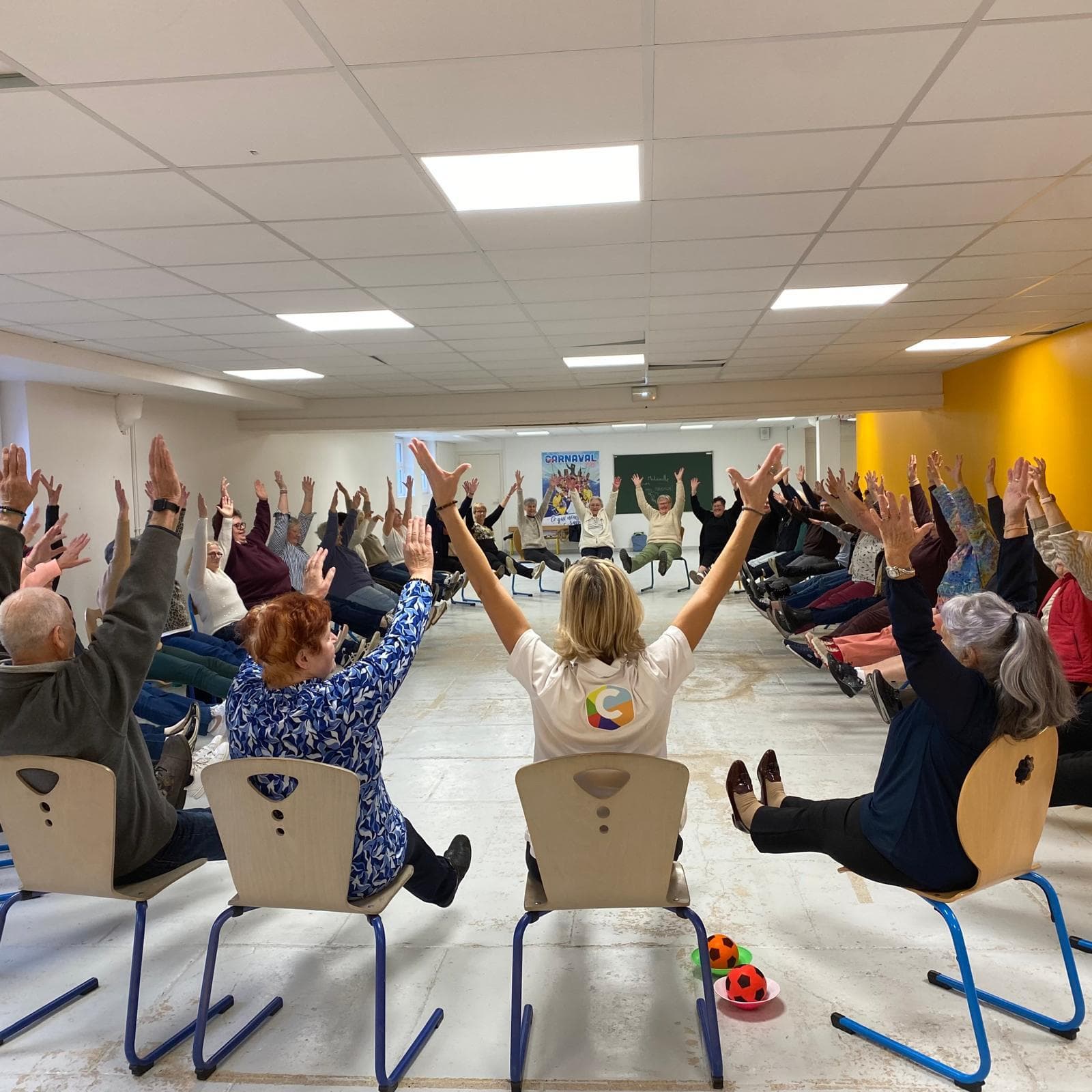 Des seniors en séance CREADIAZ®, bras levés sur leur chaise, guidés par une animatrice